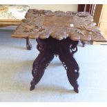 An early/mid 20thC (probably Indian) fruitwood occasional table, raised on a foliate carved, folding
