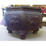 An Oriental cast bronze octagonal jardinière with opposing handles, decorated in high relief with