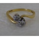 An 18ct gold, two stone, claw set diamond crossover ring