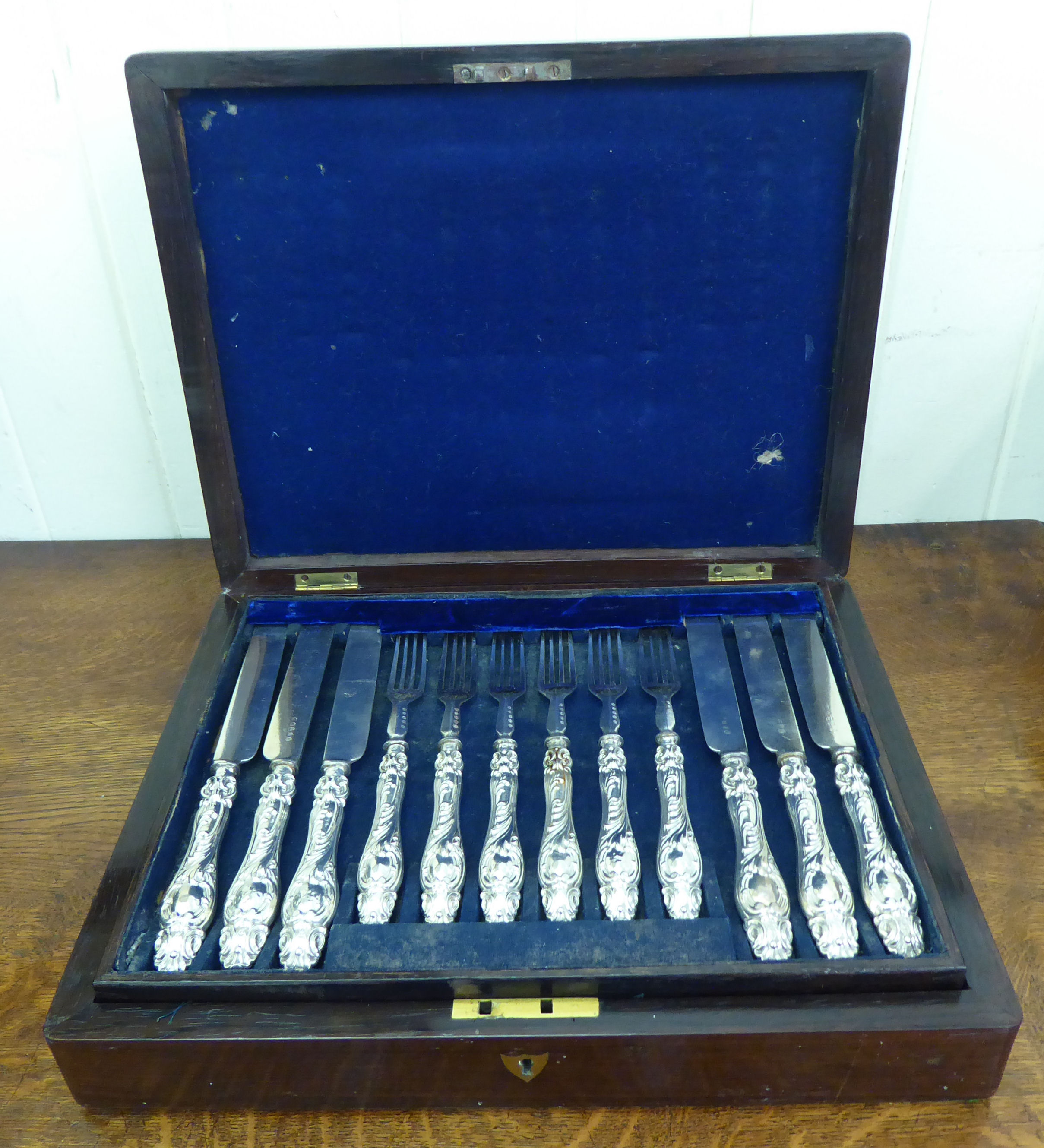 A set of eighteen Victorian silver plated fruit knives and forks, on scroll moulded silver handles