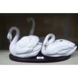 A series of three Lladro china swans, mounted on a wooden plinth  10"h