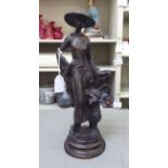 A 20thC cast and burnished bronze standing figure, a fashionable young woman beside a flower vase,