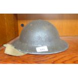 A World War II tin helmet with a canvas strap  (Please Note: this lot is subject to the statement