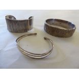 Three dissimilar silver bangles: to include one hinged with a textured finish