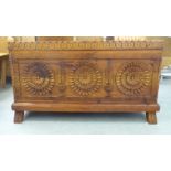 A mid 20thC Chinese stained fruitwood chest with a hinged lid and an ornately carved front, raised