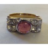 An Art Deco bi-coloured gold ring, set with an unidentified central stone, flanked by eight diamonds
