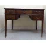 An early 20thC mahogany five drawer kneehole writing table, raised on square, tapered legs and