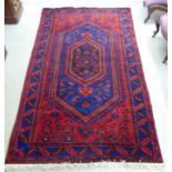 A Persian rug, decorated with repeating stylised designs, in bright colours  51" x 92"