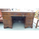A modern mahogany finished nine drawer twin pedestal desk, the top set with a tooled green hide