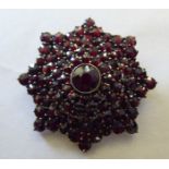 A yellow metal and garnet set circular brooch