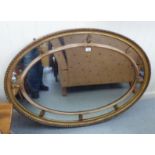 A 19thC mirror, the oval plate set in a sectioned gilded frame  34" x 48"