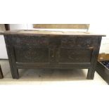 An early 18thC oak coffer with straight sides and a hinged lid, over a carved panelled front, raised
