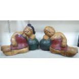 A pair of modern Asian carved and painted wooden figures, a man and a woman, resting on pillows