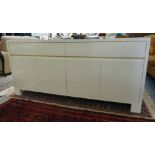 A modern cream coloured laminate sideboard with two in-line drawers, over four cupboard doors,