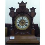 A late 19thC American walnut cased mantel clock with carved ornament; the Ansonia gong strike