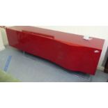 A modern red high gloss laminate finished sideboard, the four inline compartments enclosed by a