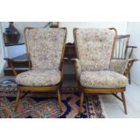 Two similar Ercol beech framed high, spindled, wingback armchairs with floral tapestry cushioned