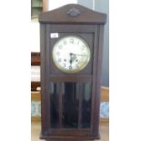 An early 20thC oak cased wall clock with a bevel glazed pendulum window; the movement faced by a