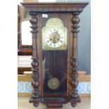 A late 19thC walnut cased Vienna timepiece with a full-height, glazed door, faced by a brass and