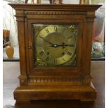 An early 20thC carved walnut cased mantel clock; the gong strike movement faced by a brass and