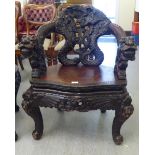 A late Victorian dark stained and profusely carved open arm chair, decorated in Sino-European