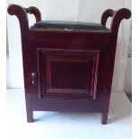 An Edwardian mahogany piano stool with a padded seat, over a cupboard door, raised on block legs
