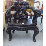 A late Victorian dark stained and profusely carved open arm chair, decorated in Sino-European