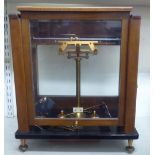 A 20thC Stanton Morden glazed, teak cased, lacquered brass set of balance scales  12"h  5"w