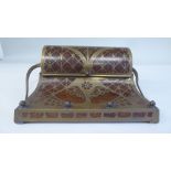 An Art Nouveau hardwood inkstand, intricately overlaid in brass with swept loop handles, the