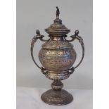 A silver twin handled golf trophy cup and cover with a figural finial, on a knopped pedestal foot,