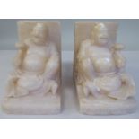 A pair of Chinese carved soapstone bookends, each featuring a seated, robed figure holding a lotus