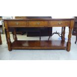 A modern Old English style oak dresser with three inline drawers, raised on turned and block