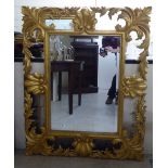 A modern mirror, the bevelled plate set in a shell and foliate carved gilt frame  36" x 44"