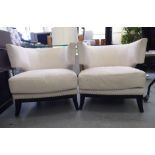 A pair of modern stud upholstered cream coloured fabric covered armchairs, raised on splayed