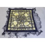 An embroidered yellow on black shawl, decorated with birds, flora and foliage with a tasselled