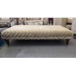 A modern two tone fabric covered footstool, raised on turned, tapered legs