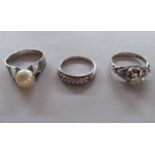 A white gold ring  stamped 18k, set with a single diamond; a half eternity ring; and a pearl set