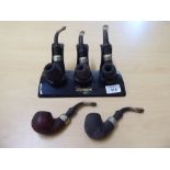 A group of five Peterson of Dublin smokers pipes, three on stands  8"w