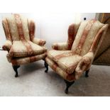 A pair of mid 20thC wingback armchairs, upholstered in striped red and yellow fabric, raised on