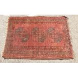 An Afghan rug, decorated with three central guls and bordered with floral imagery, on a red