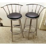 A pair of modern chromium framed bar stools with black vinyl seats