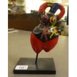 In the manner of Niki de Saint Phalle, a painted paper mache figure, on a plinth  7"h