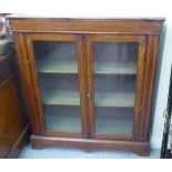 An Edwardian inlaid mahogany cabinet bookcase, enclosed by a pair of full height, glazed panelled