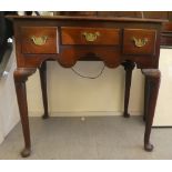 A George III oak lowboy with three short drawers, over a shaped apron with brass bail handles,