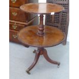 An early 19thC mahogany two tier dumb waiter, elevated on a turned column and a splayed tripod base,