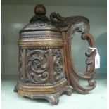 A 19thC carved wooden peg tankard with a hinged cover and finial  11"h