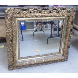 A late 19thC mirror, the bevelled plate set in a shell, C-scrolled and foliate moulded gilt frame