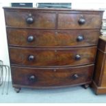 A late Victorian mahogany bow front, five drawer dressing chest with bun handles, raised on turned