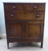 An early 20thC oak cupboard, comprising two short/one long drawers, over a pair of panelled doors,