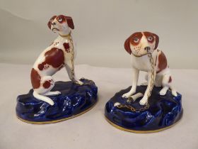 A pair of Staffordshire pottery models, seated, malevolent hounds, each set on a gilded midnight